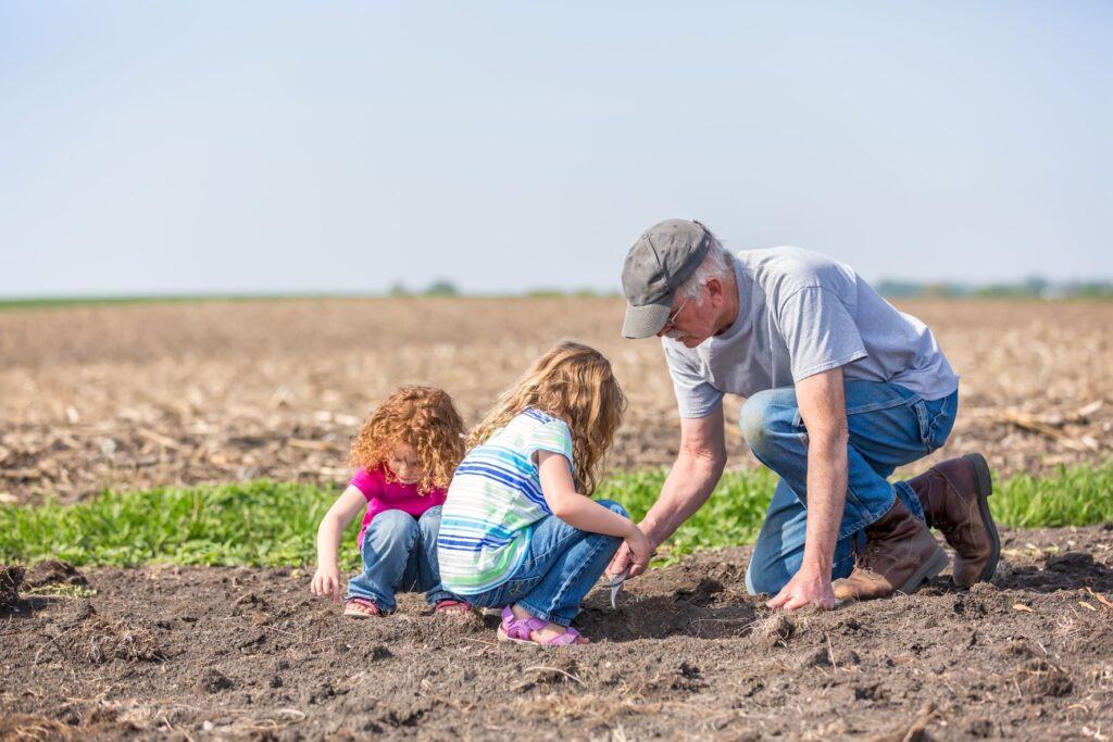 Farmer in field with grandchildren