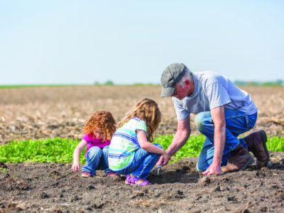 Farmer in field with grandchildren